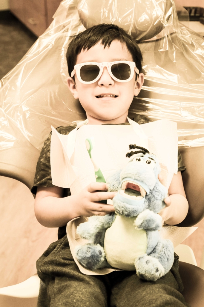 Boy in dental chair holding a stuffed animal